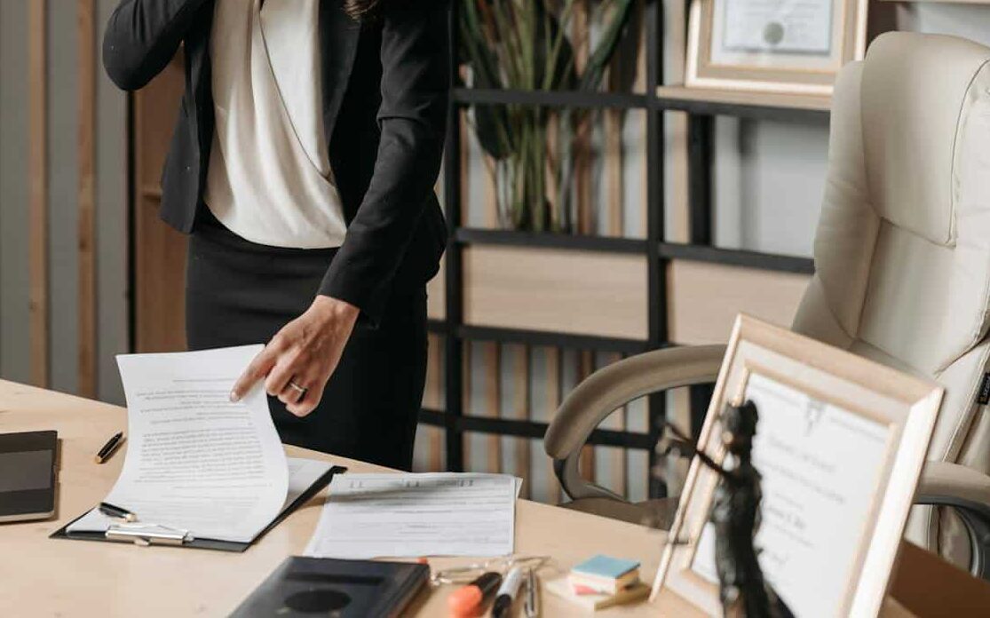 A female lawyer talking on phone while reviewing legal documents in a modern office setting.