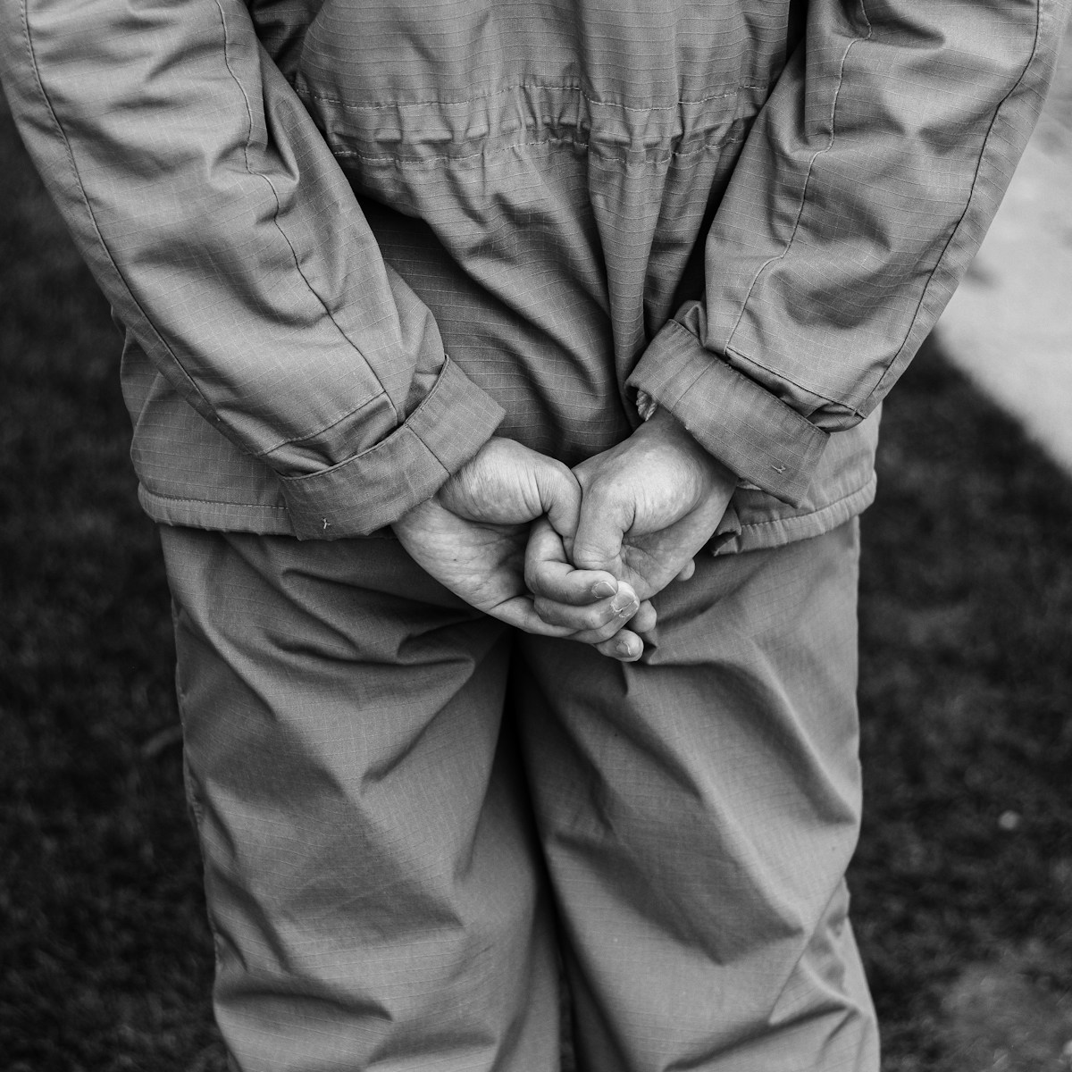 grayscale photo of man in jacket and pants holding hands